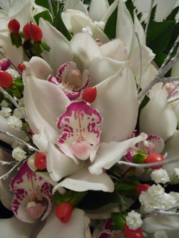 Centre de table avec des cymbidiums, du gypsophile et des baies de millepertuis