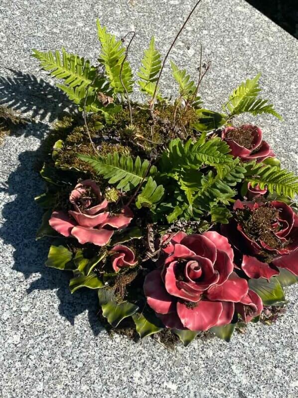 Fougères et mousses dans une couronne de fleurs artificielles en été dans le cimetière du Père Lachaise, Paris 20e (75)