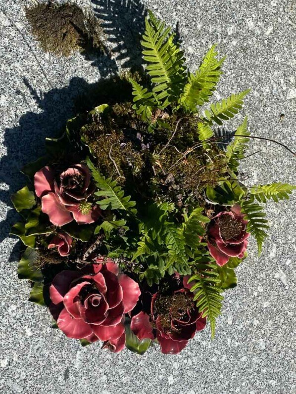 Fougères et mousses dans une couronne de fleurs artificielles en été dans le cimetière du Père Lachaise, Paris 20e (75)